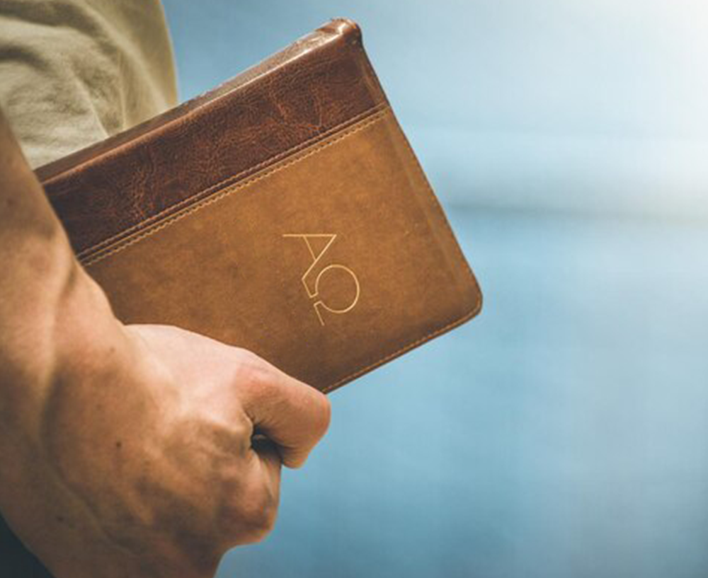 man holding a bible with alpha and omega symbols