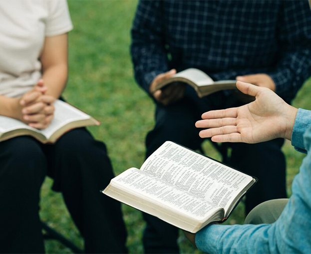 3 people sitting and holding a bible