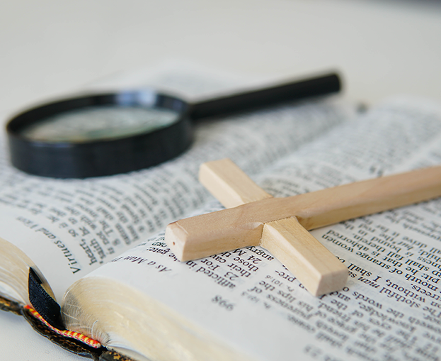 a cross and magnifying glass on the Bible